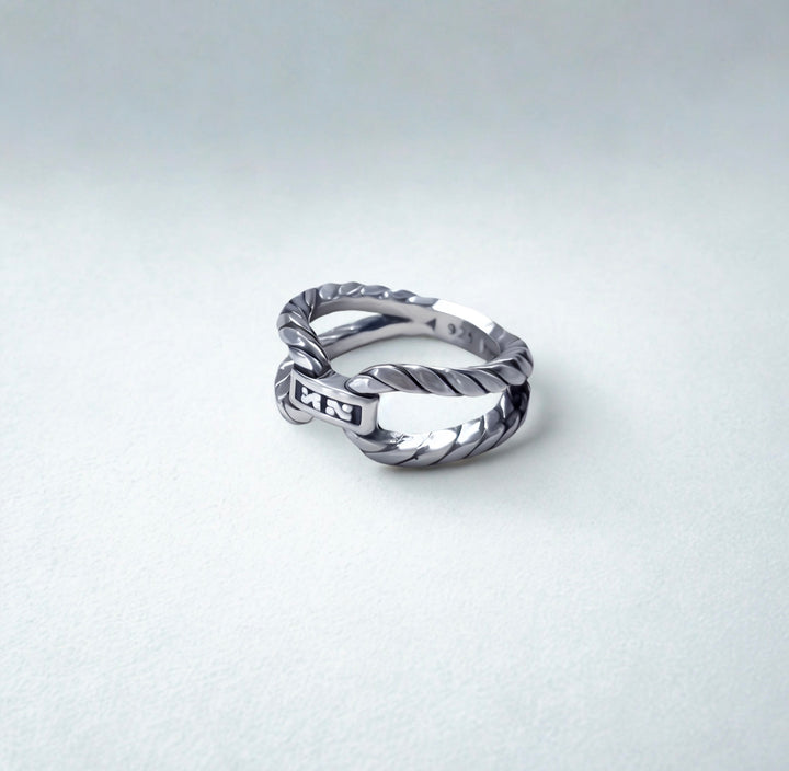 Silver ring with twisted design on a light gray background
