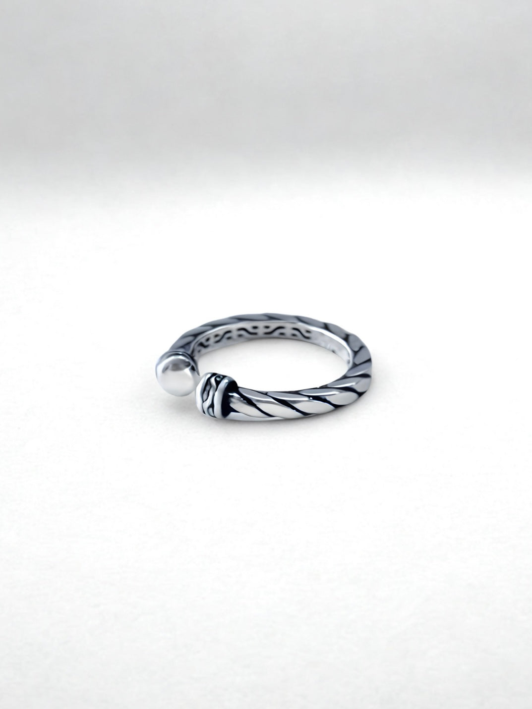 Silver ring with a textured design on a white background